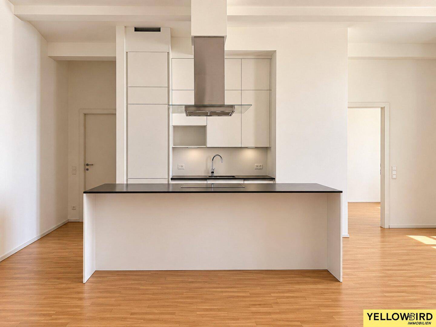 Moderne Einbauküche mit weißer Kücheninsel und dunkler Arbeitsplatte in einem offenen Wohnbereich.
