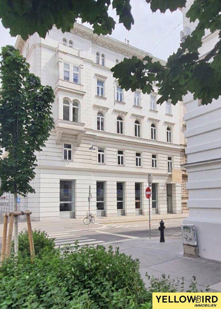 Historisches Gebäude mit klassischer Fassade an einer städtischen Kreuzung, das eine beeindruckende Architektur zeigt.