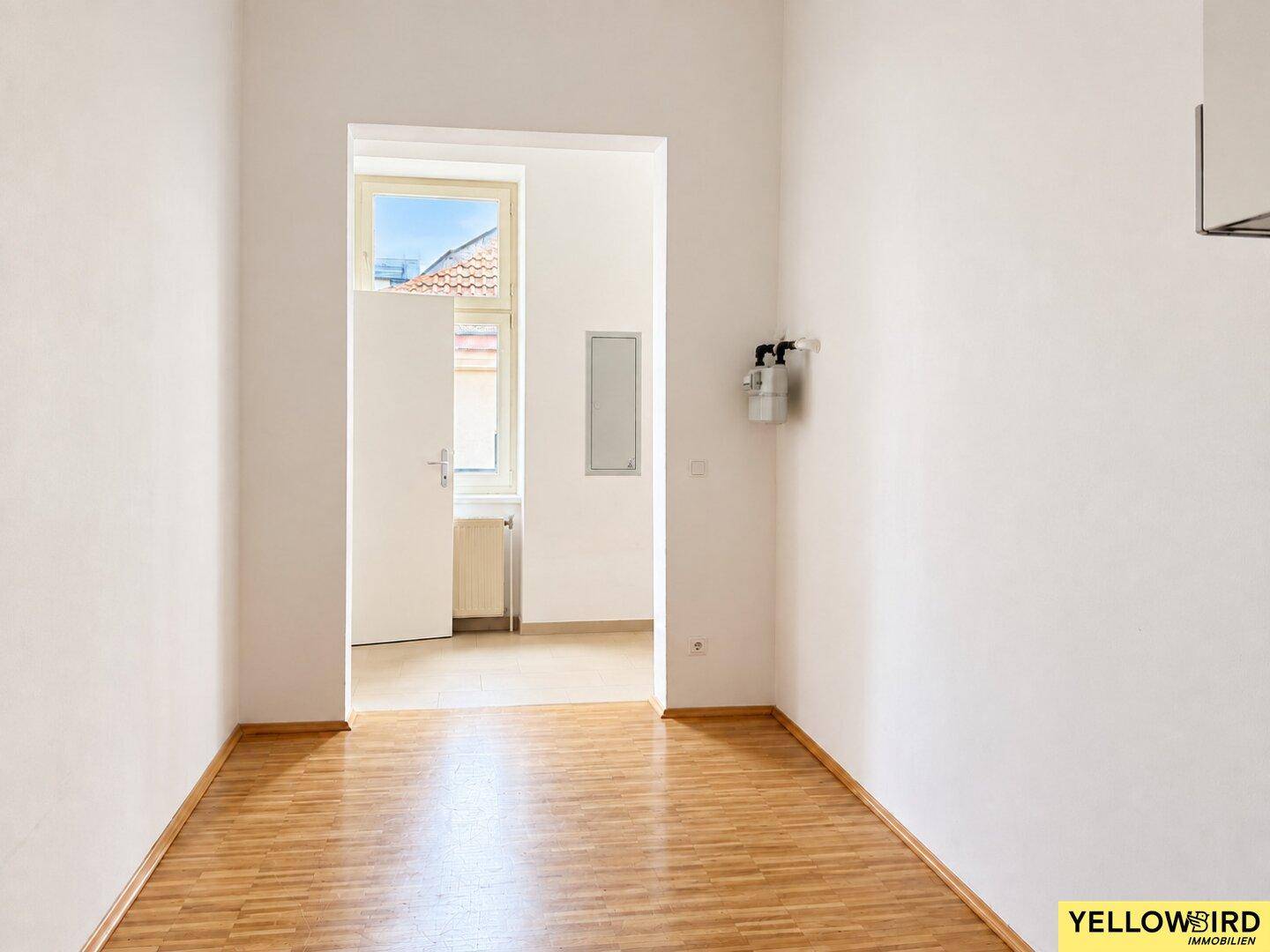 Heller Durchgangsbereich mit Holzfußboden, der zu einem weiteren Raum führt.