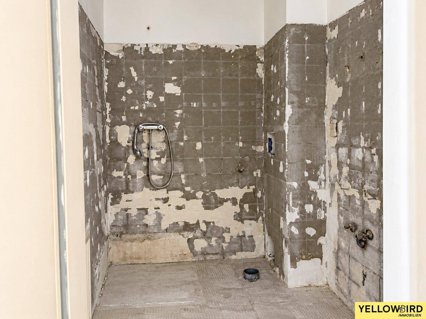 Badezimmer im Rohzustand mit Duschanschluss, bereit für die Sanierung.