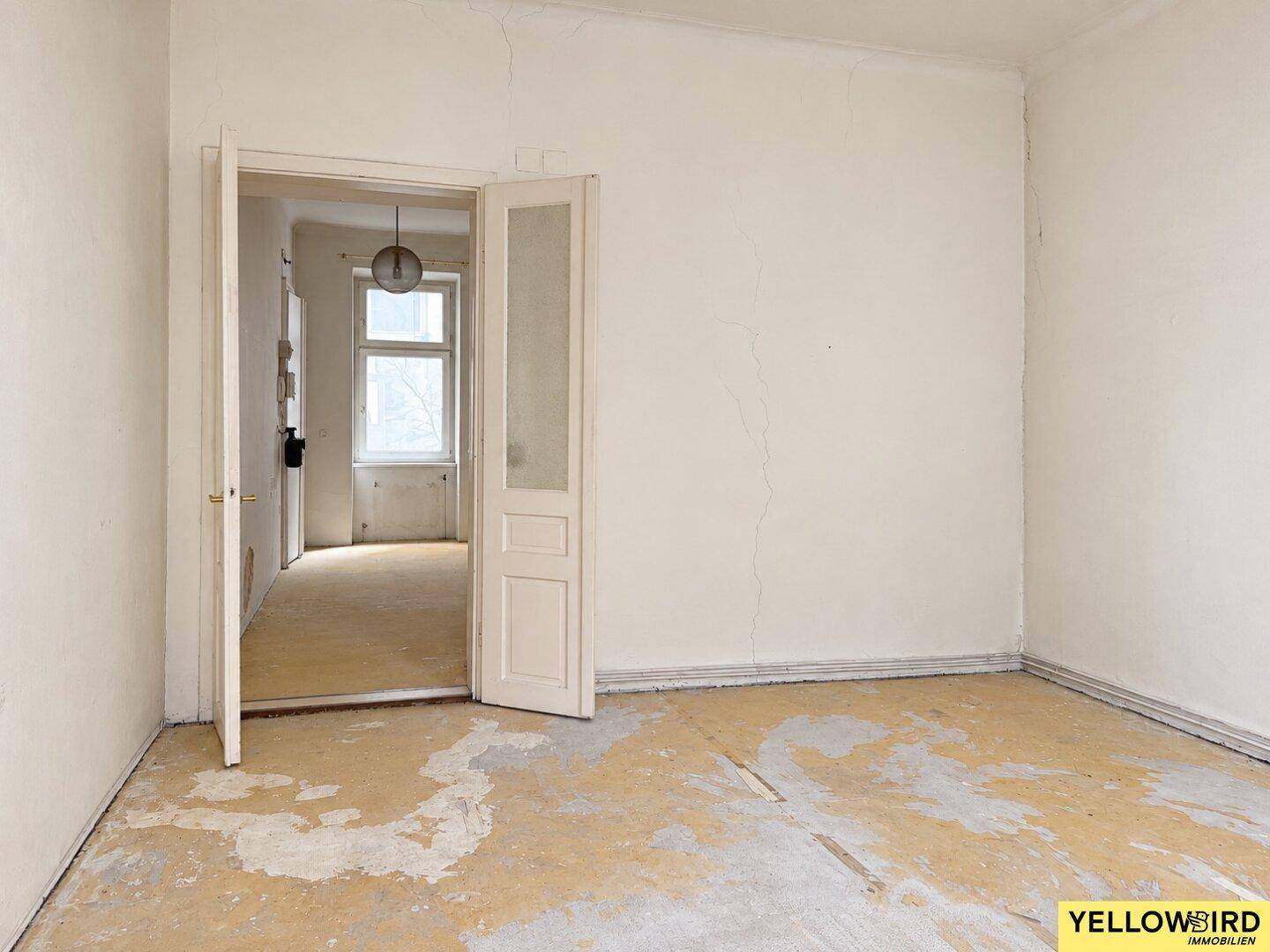 Leerer Raum mit offener Doppeltür, die zu einem weiteren Zimmer führt, bereit zur Gestaltung.
