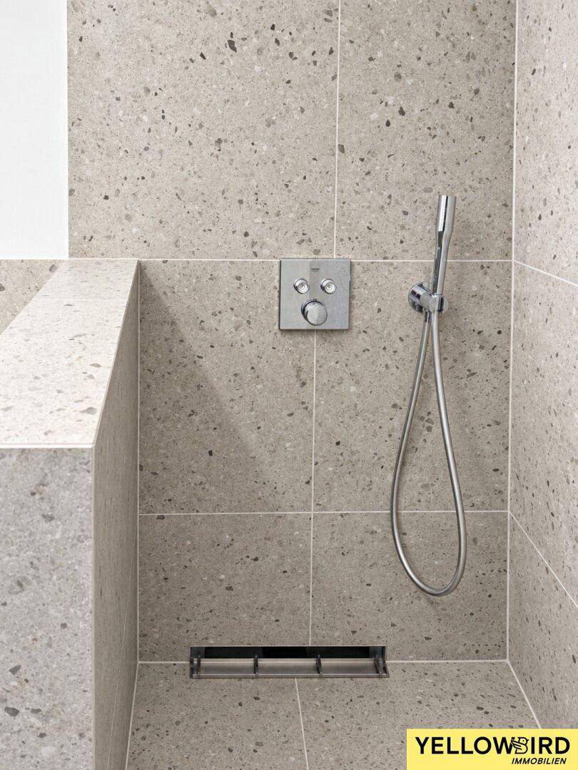 Detailansicht der modernen begehbaren Dusche mit grauen Fliesen und hochwertigen Armaturen.