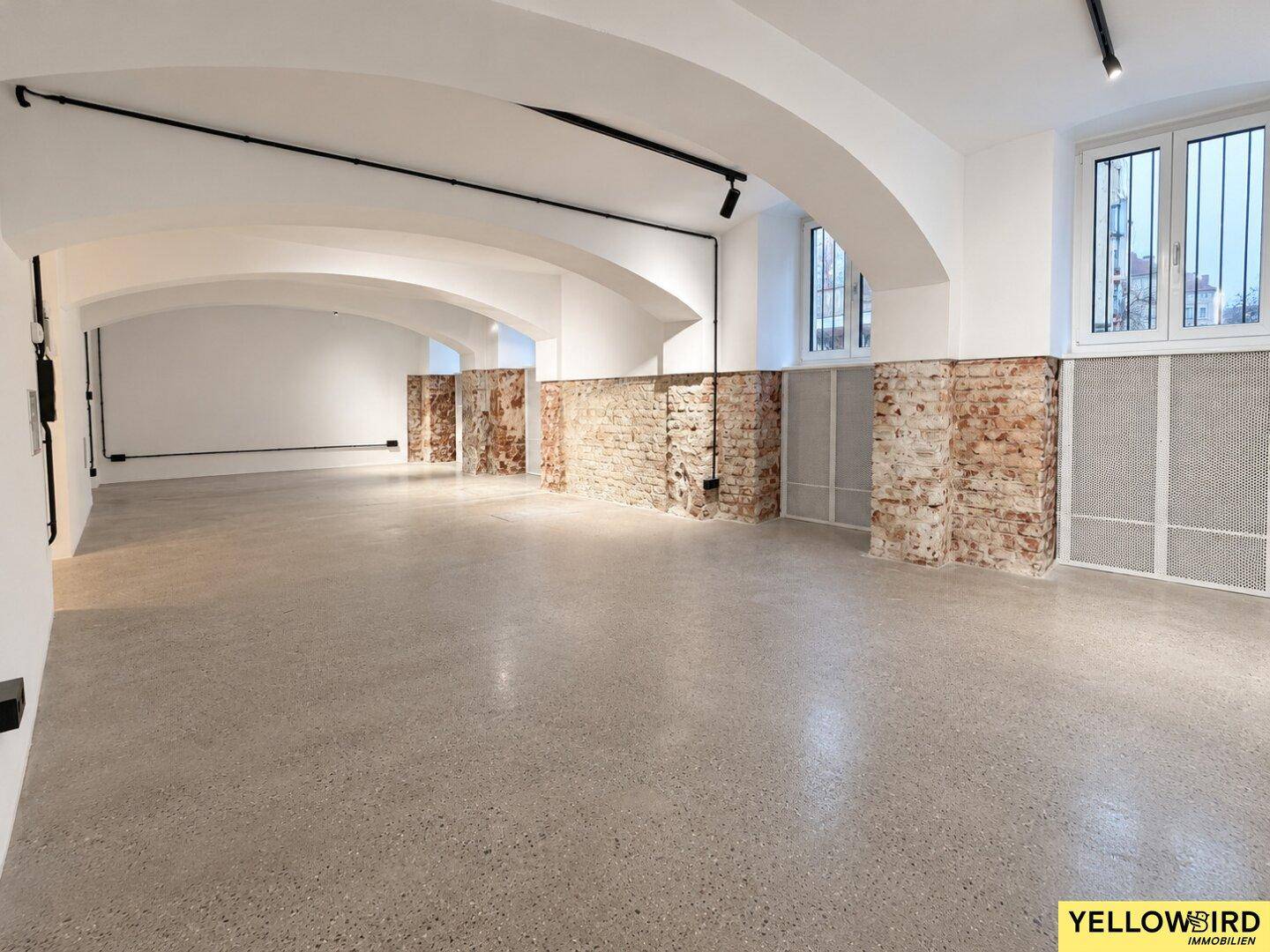 Weitläufiger, offener Raum mit beeindruckenden Gewölbedecken und industriellem Betonboden.