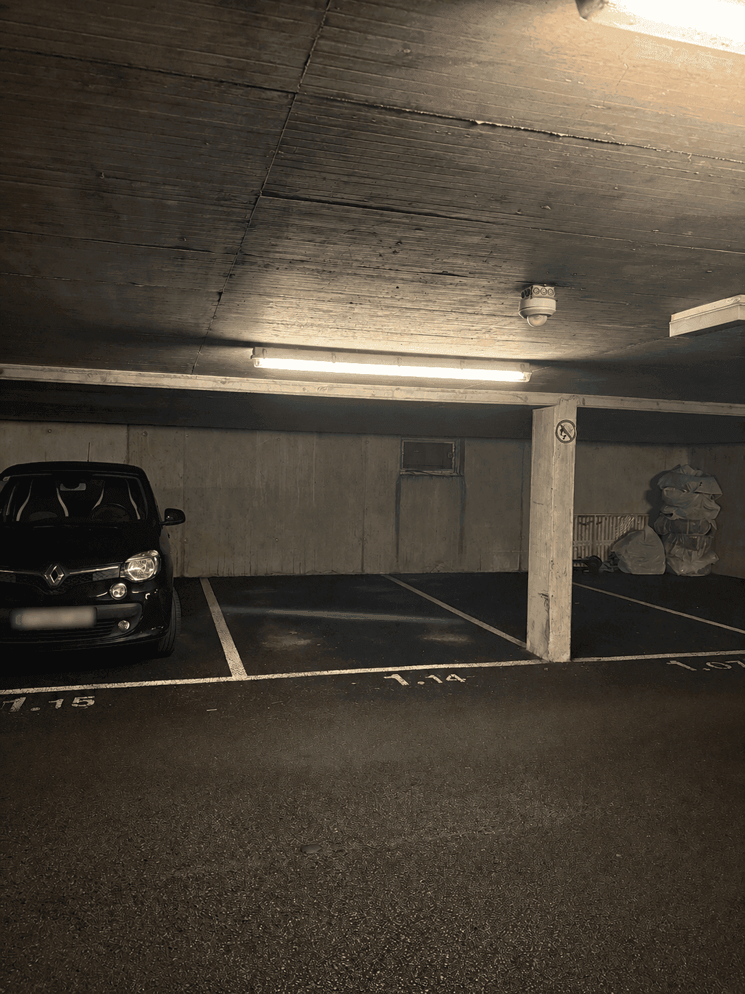 Tiefgaragenstellplatz mit einem geparkten Auto, Betonwänden und Deckenbeleuchtung.