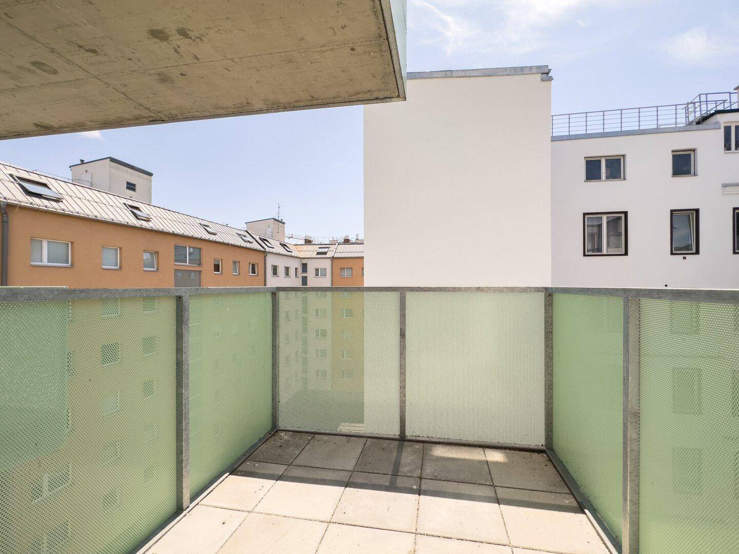 Heller Balkon mit Fliesenboden und Blick auf die umliegenden Gebäude der Stadt.