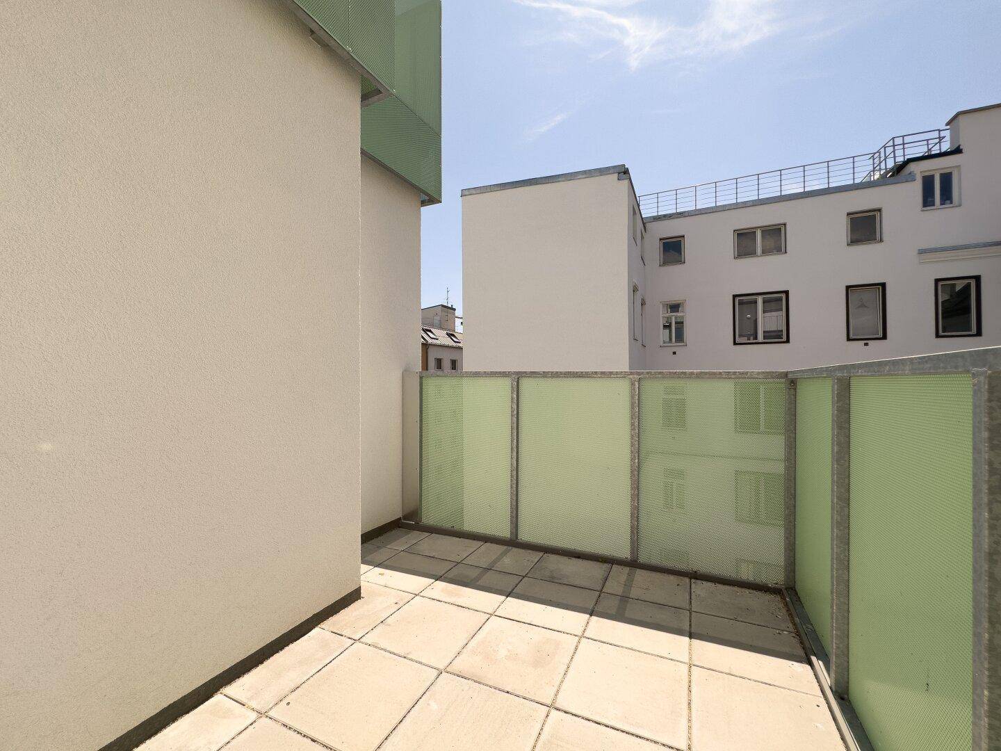 Geräumiger Balkon mit Fliesenboden und Blick auf den Innenhof der Wohnanlage.