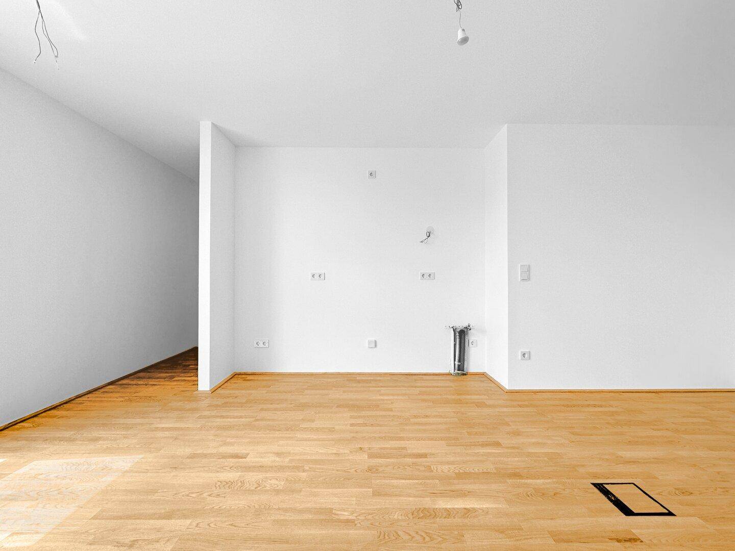 Geräumiger, heller Innenraum mit Holzboden und weißen Wänden, ideal für offene Wohnkonzepte.