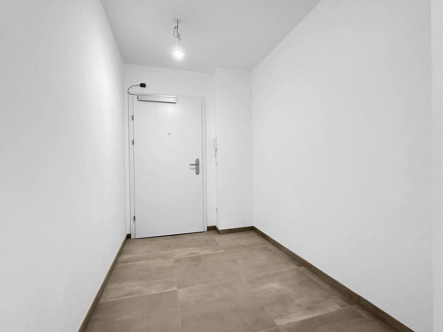 Heller Eingangsbereich mit Fliesenboden und einer modernen Wohnungstür.