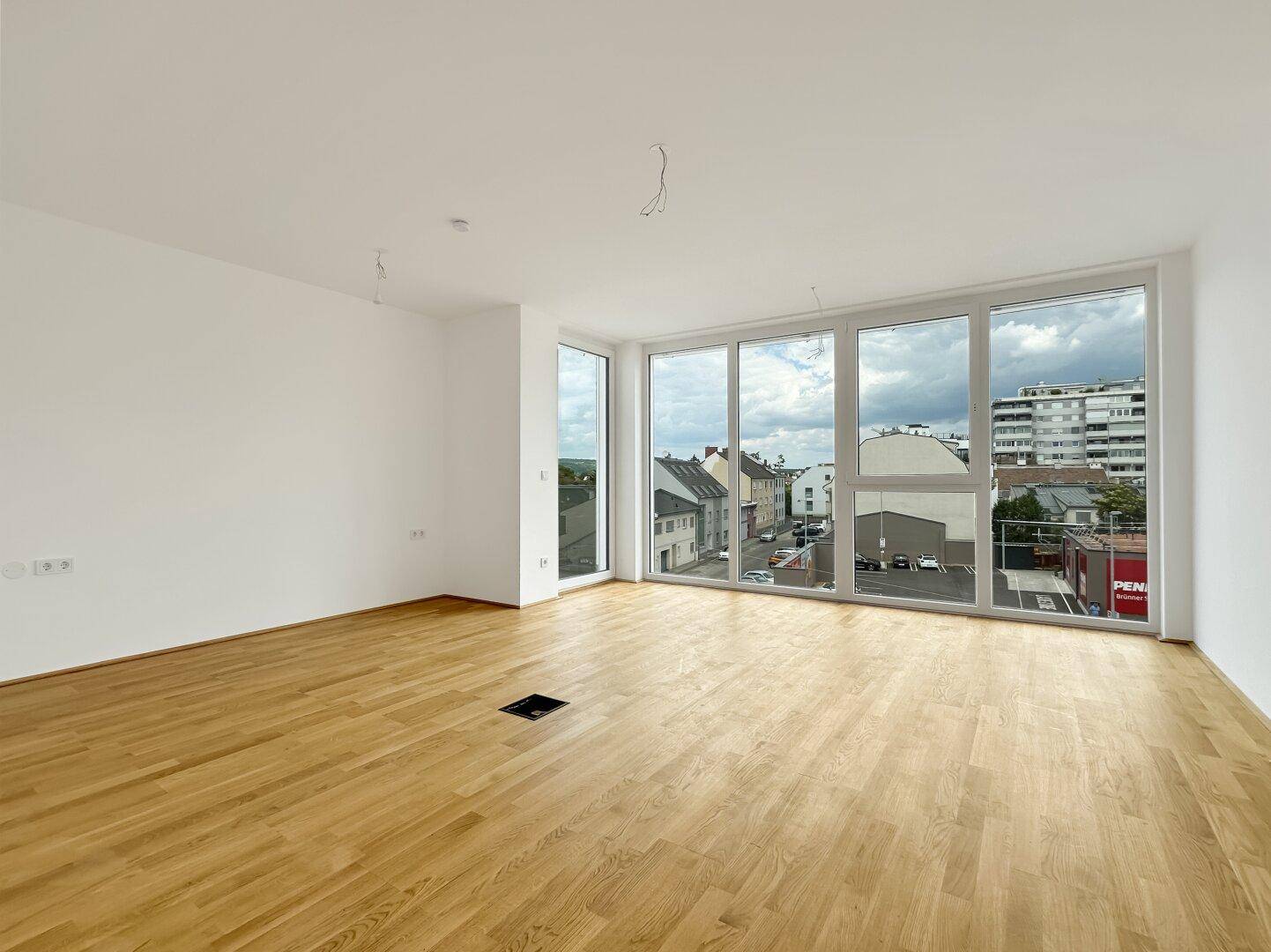 Geräumiges, lichtdurchflutetes Wohnzimmer mit Parkettboden und Blick auf die Stadt.