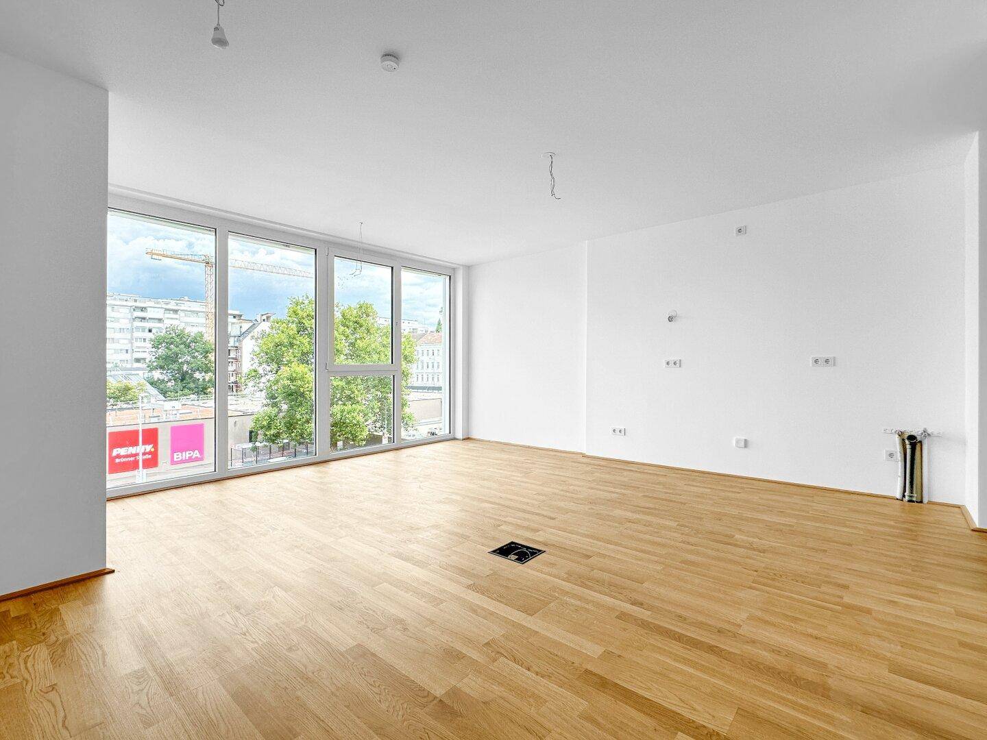 Heller Wohnbereich mit großen Fenstern, Holzboden und urbanem Ausblick.
