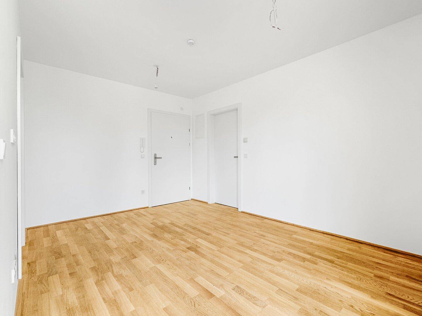 Leerer Raum mit hellem Holzboden und weißen Wänden, bereit zur individuellen Gestaltung.