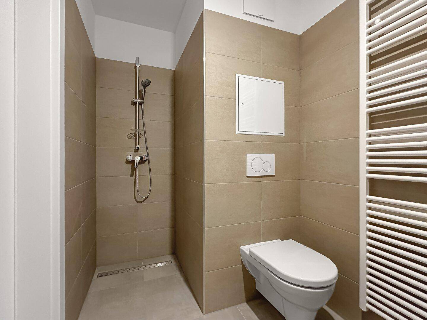 Modernes Badezimmer mit beigefarbenen Fliesen, ebenerdiger Dusche und wandhängendem WC.