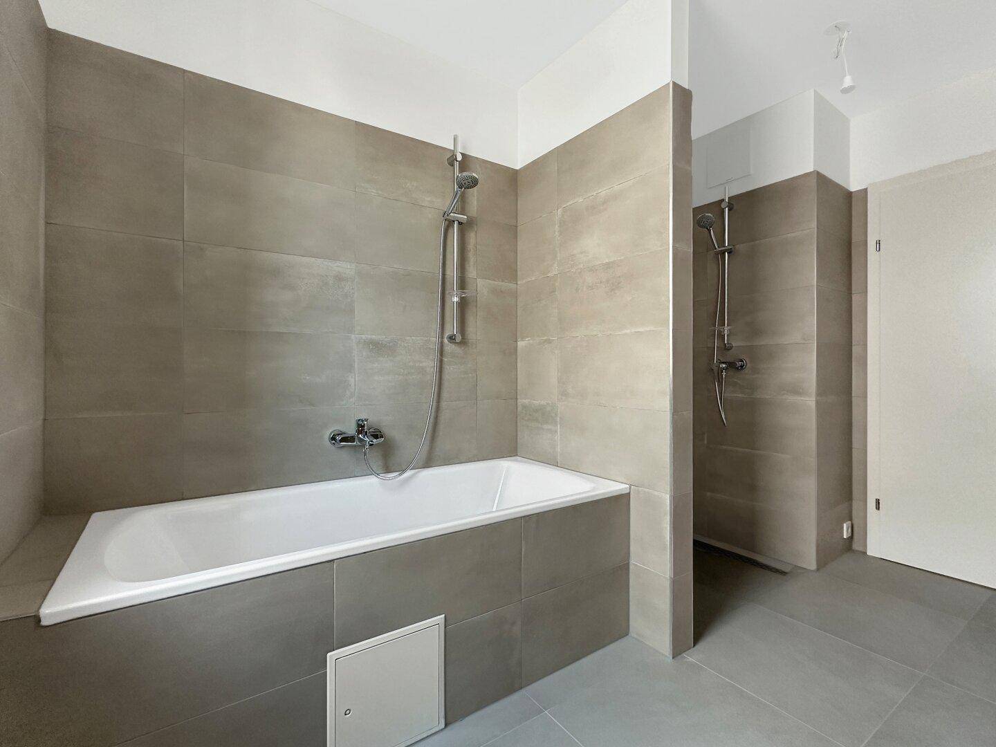 Geräumiges Badezimmer mit Badewanne und separater Duschkabine, ausgestattet mit modernen Armaturen.