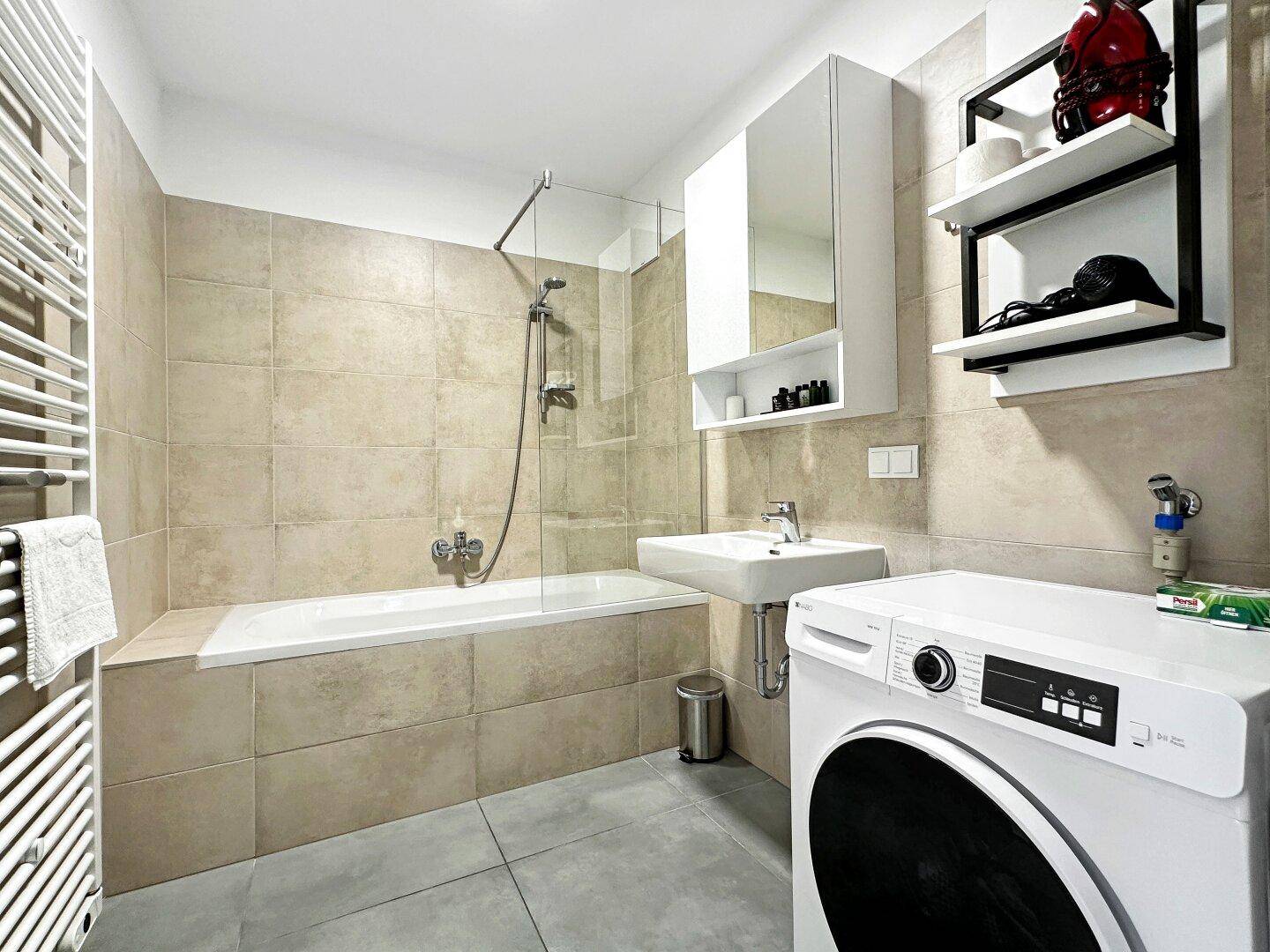 Modernes Badezimmer mit Badewanne, Dusche, Waschbecken und Waschmaschine.