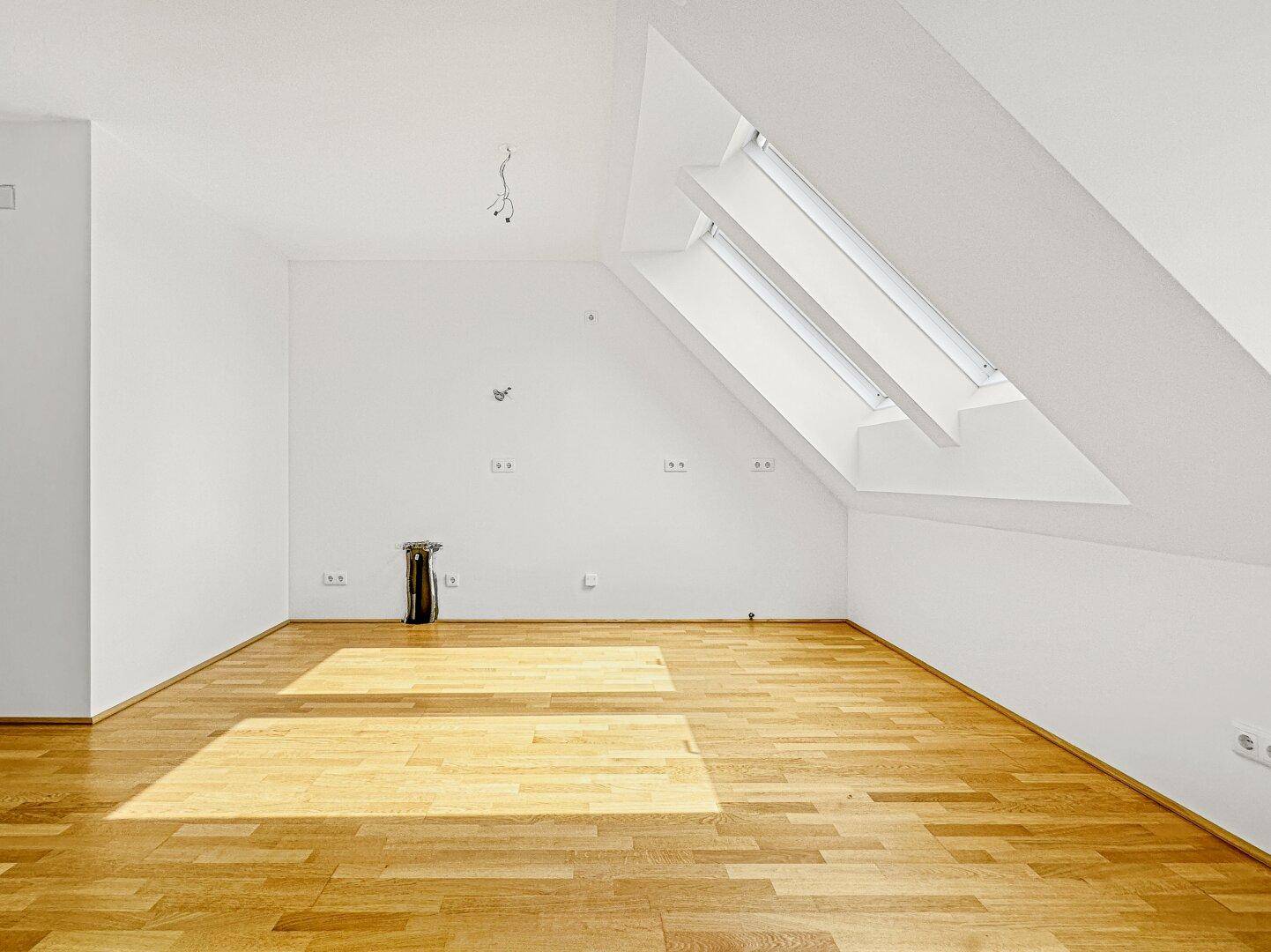 Geräumiges, helles Zimmer im Dachgeschoss mit Holzboden und zwei großen Dachfenstern.