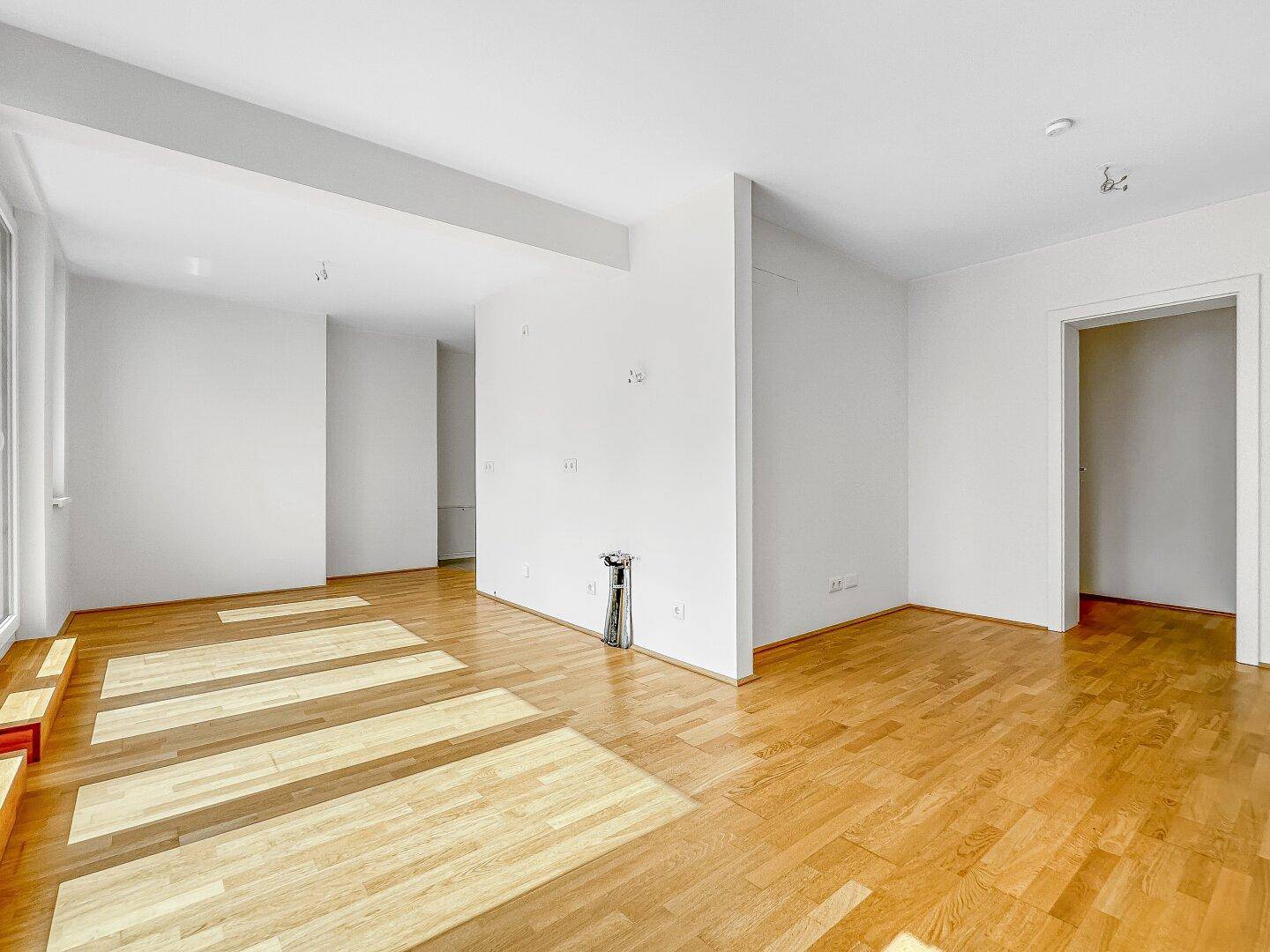 Geräumiger, leerer Raum mit Holzboden und weiß gestrichenen Wänden, ideal für individuelle Gestaltung und vielseitige Nutzung.