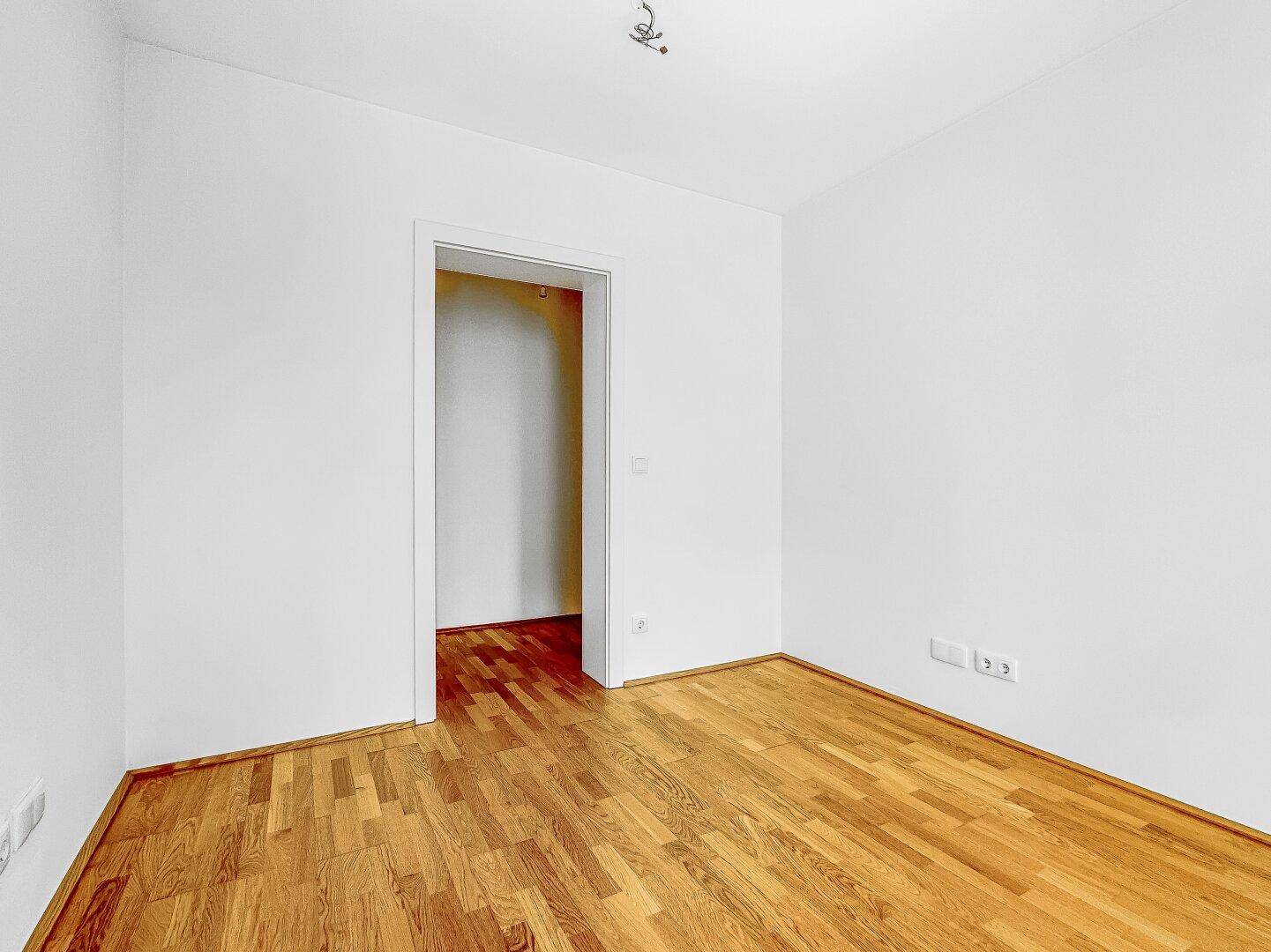 Kleiner, heller Raum mit Holzboden und weiß gestrichenen Wänden, bereit zur Einrichtung als Schlaf- oder Arbeitszimmer.