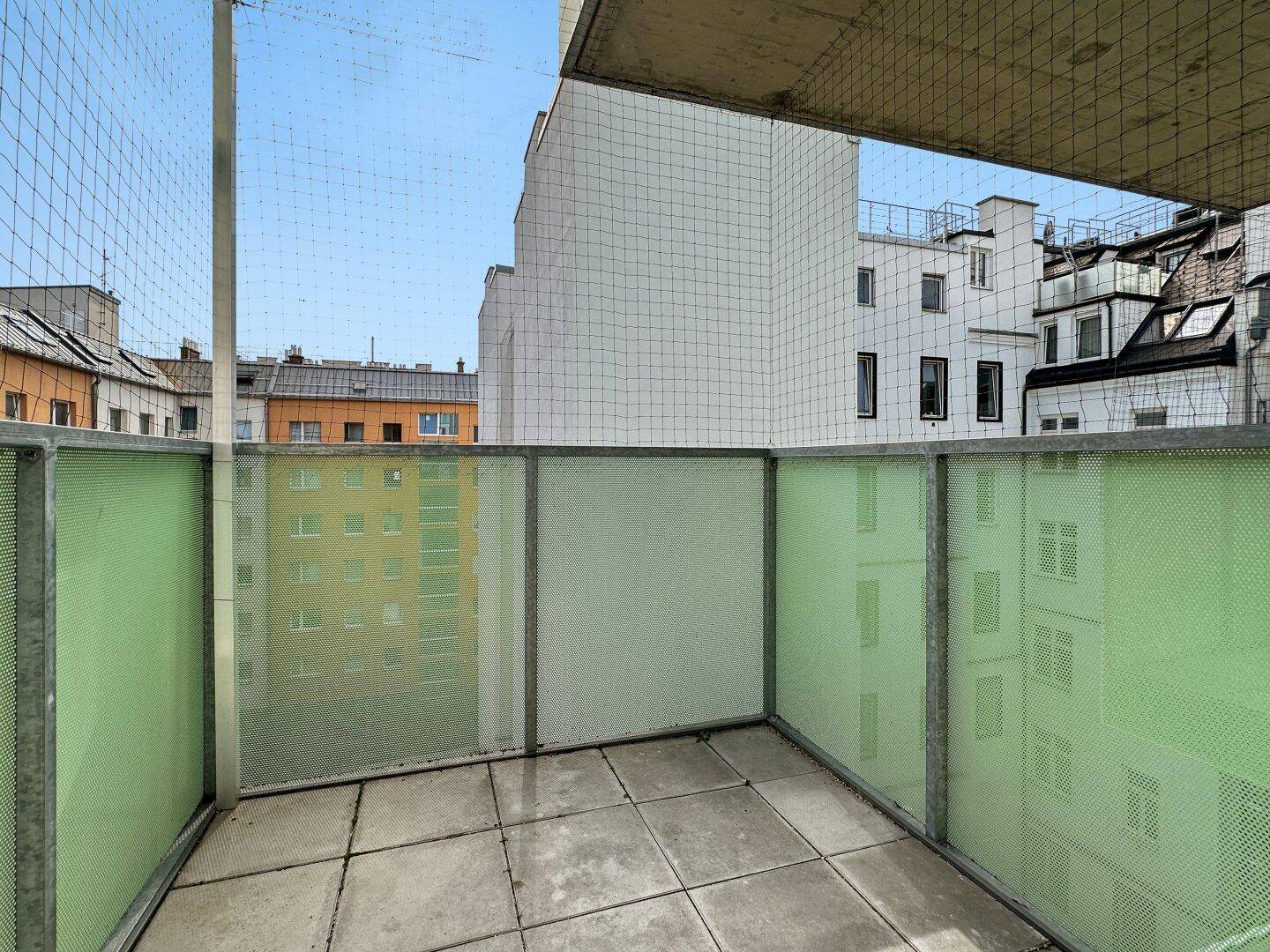 Kleiner Balkon mit Fliesenboden und Blick auf die umliegenden Stadtgebäude.