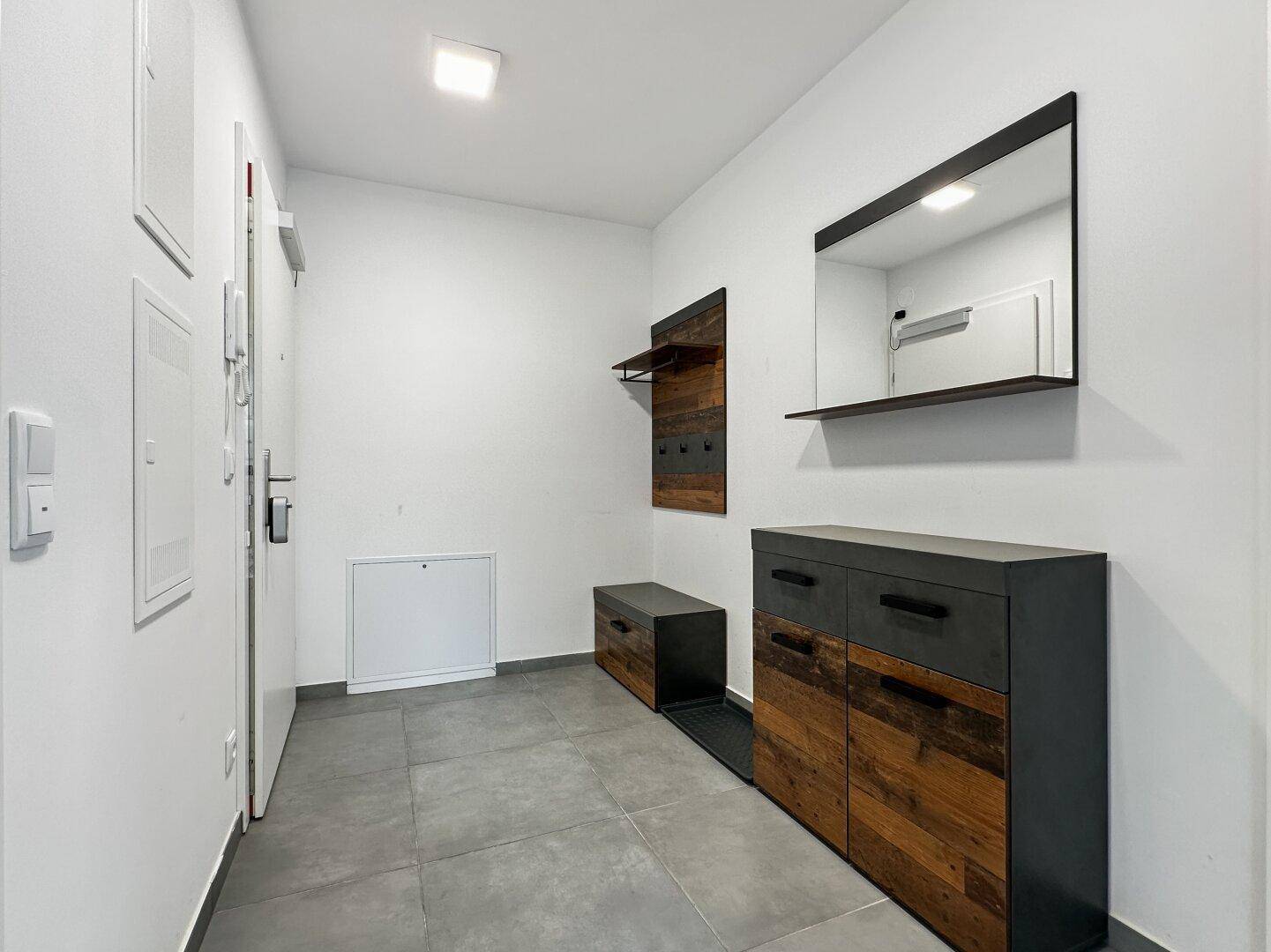 Moderner Eingangsbereich mit Fliesenboden, Garderobe und stilvoller Kommode.