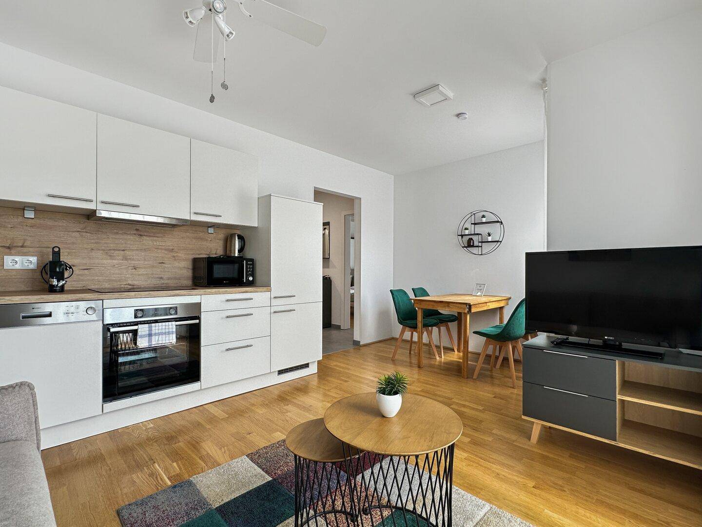 Moderner offener Wohnbereich mit integrierter Küche, Essbereich und Wohnzimmer mit Holzboden.