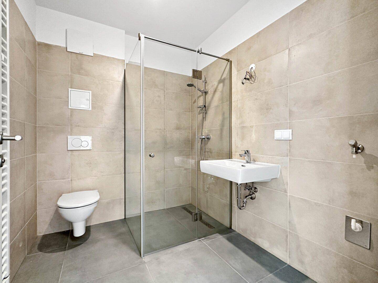 Modernes Badezimmer mit begehbarer Dusche, wandhängendem WC und Waschbecken.