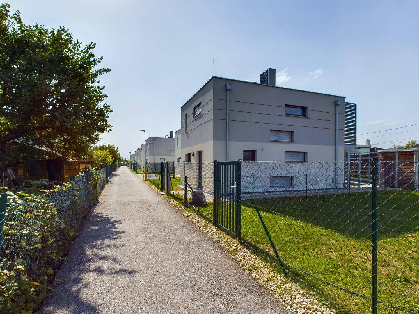 Moderne Reihenhäuser mit klaren Linien und privaten Gärten unter blauem Himmel.