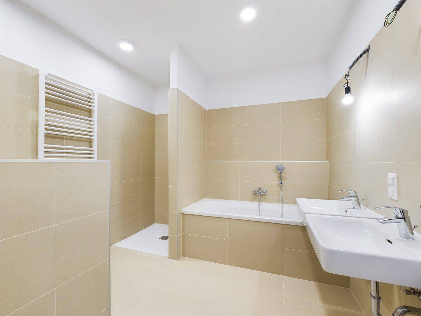 Modernes Badezimmer mit Doppelwaschbecken, Badewanne und beheiztem Handtuchhalter.