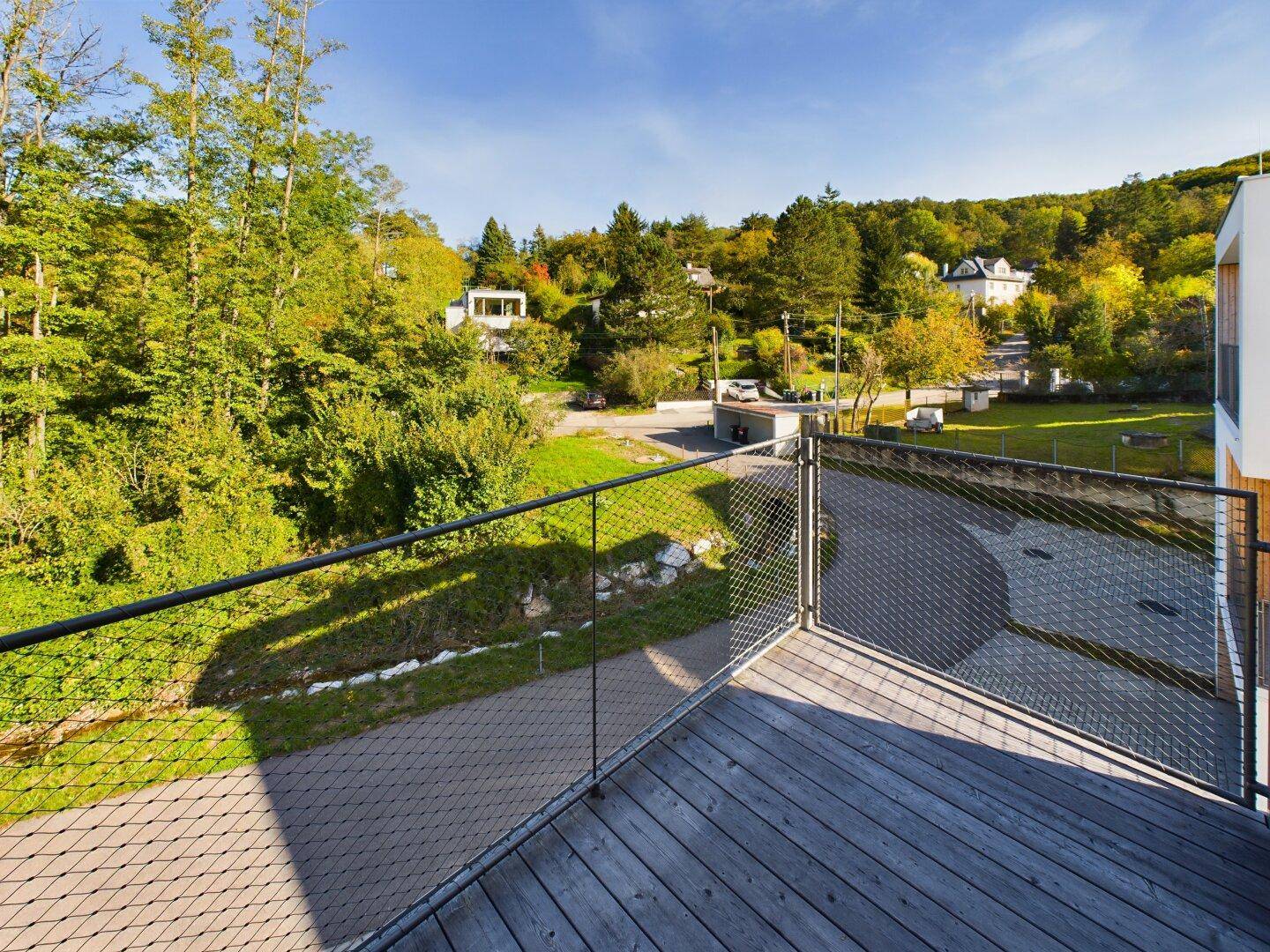 Balkon mit Holzboden und Metallgeländer bietet einen weiten Blick in die grüne Landschaft.