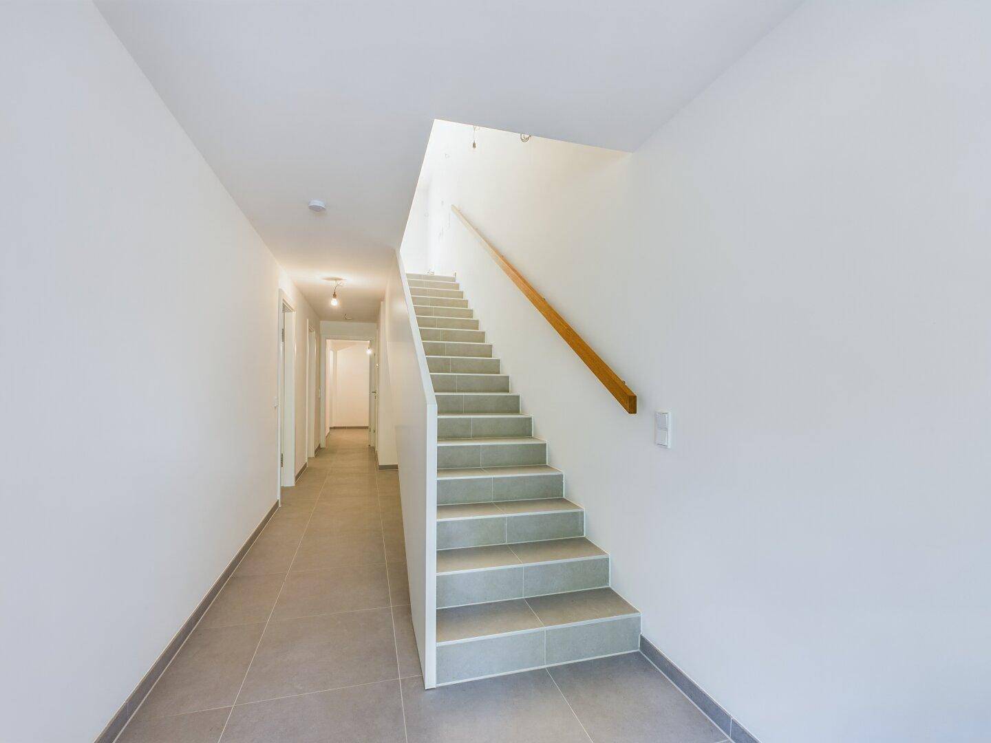 Heller Flur mit gefliester Treppe und Boden, der zu den oberen Etagen führt.