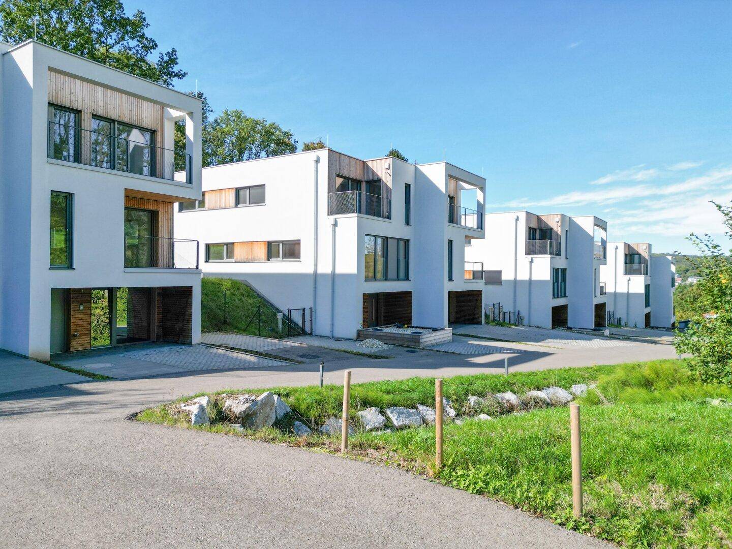 Moderne Reihenhäuser mit klaren Linien und großen Fenstern, eingebettet in eine natürliche Umgebung.