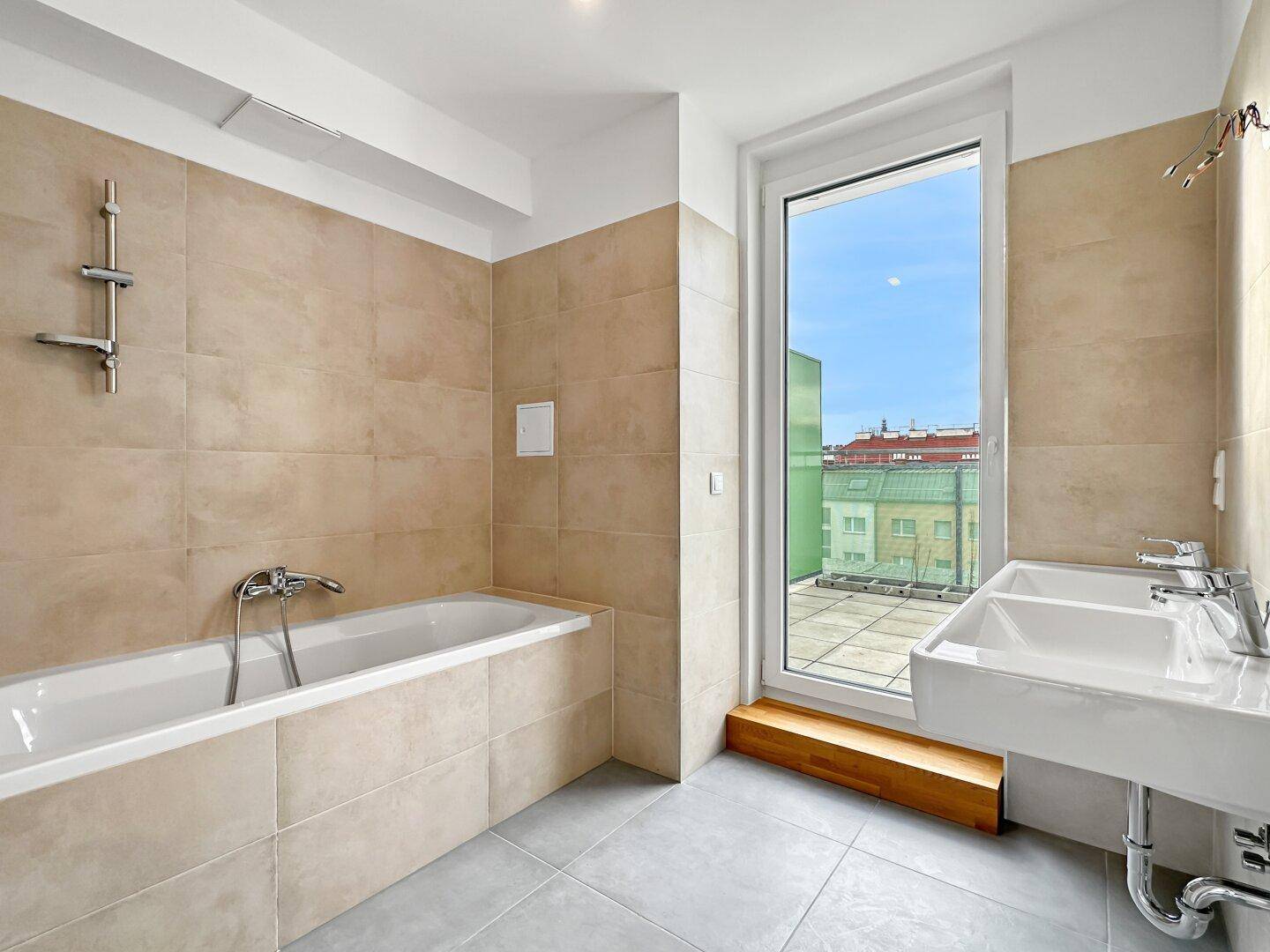 Modernes Badezimmer mit Badewanne, Doppelwaschbecken und Fenster zur Terrasse.
