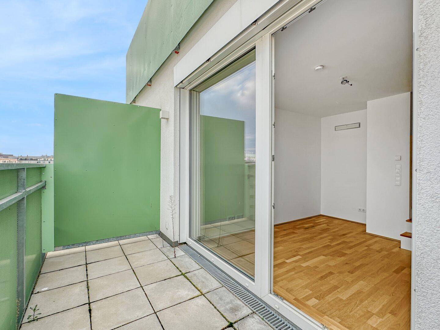 Geräumige Terrasse mit Fliesenboden und Zugang zum hellen Innenbereich der Wohnung.