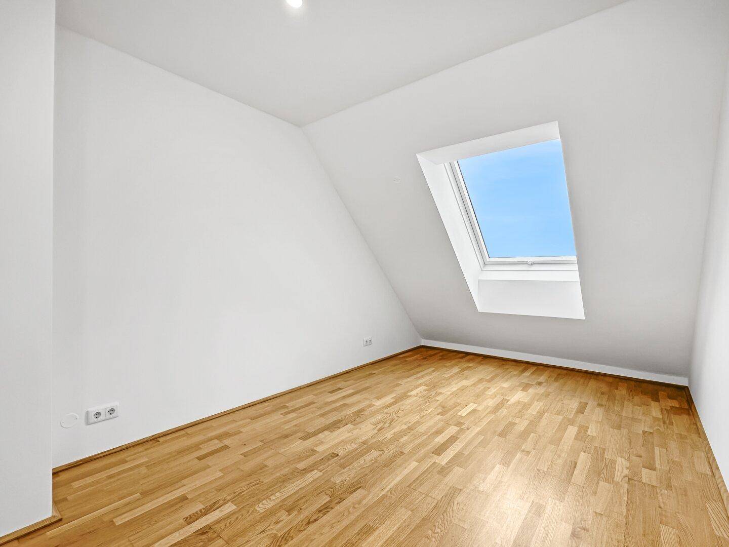 Gemütliches Schlafzimmer im Dachgeschoss mit Holzparkett und Dachfenster für viel Licht.