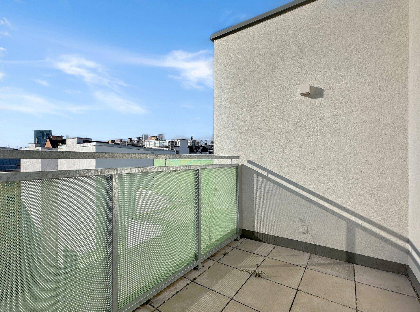 Kleiner Balkon mit Fliesenboden und moderner Brüstung, ideal für entspannte Stunden.