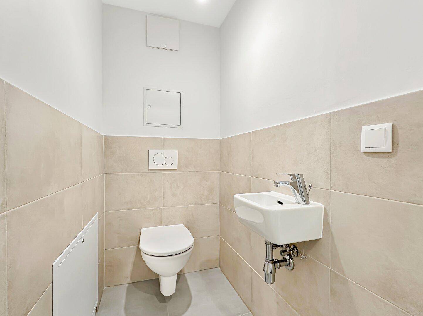 Separates Gäste-WC mit wandhängendem WC und kleinem Waschbecken.