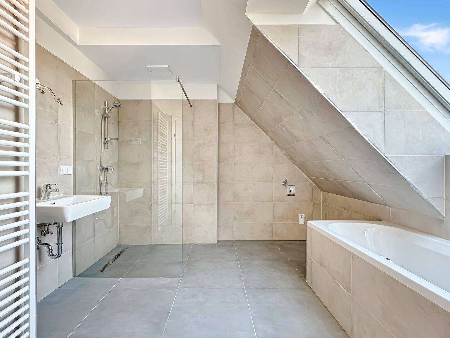 Geräumiges Badezimmer mit Badewanne, Dusche, Dachfenster und modernen Fliesen.