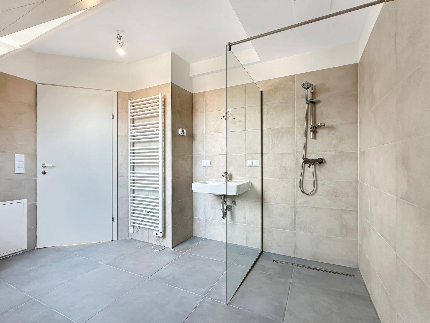 Modernes Badezimmer mit ebenerdiger Dusche, Fliesenboden und beheiztem Handtuchhalter.
