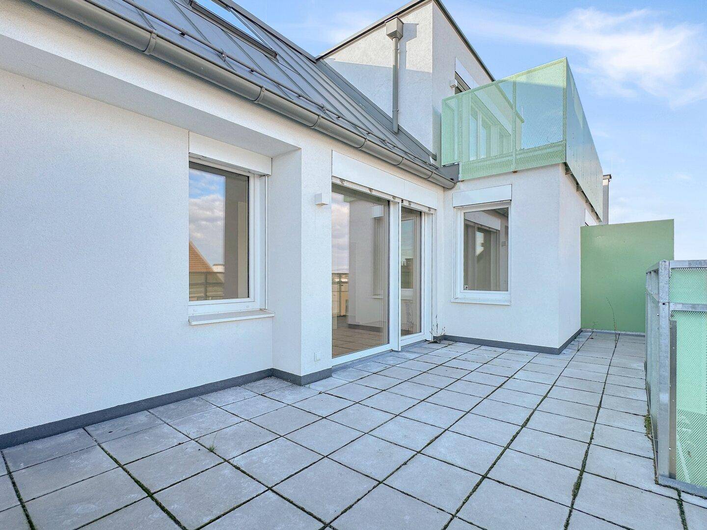 Große Terrasse mit Zugang zum Innenbereich und moderner Glasbrüstung.
