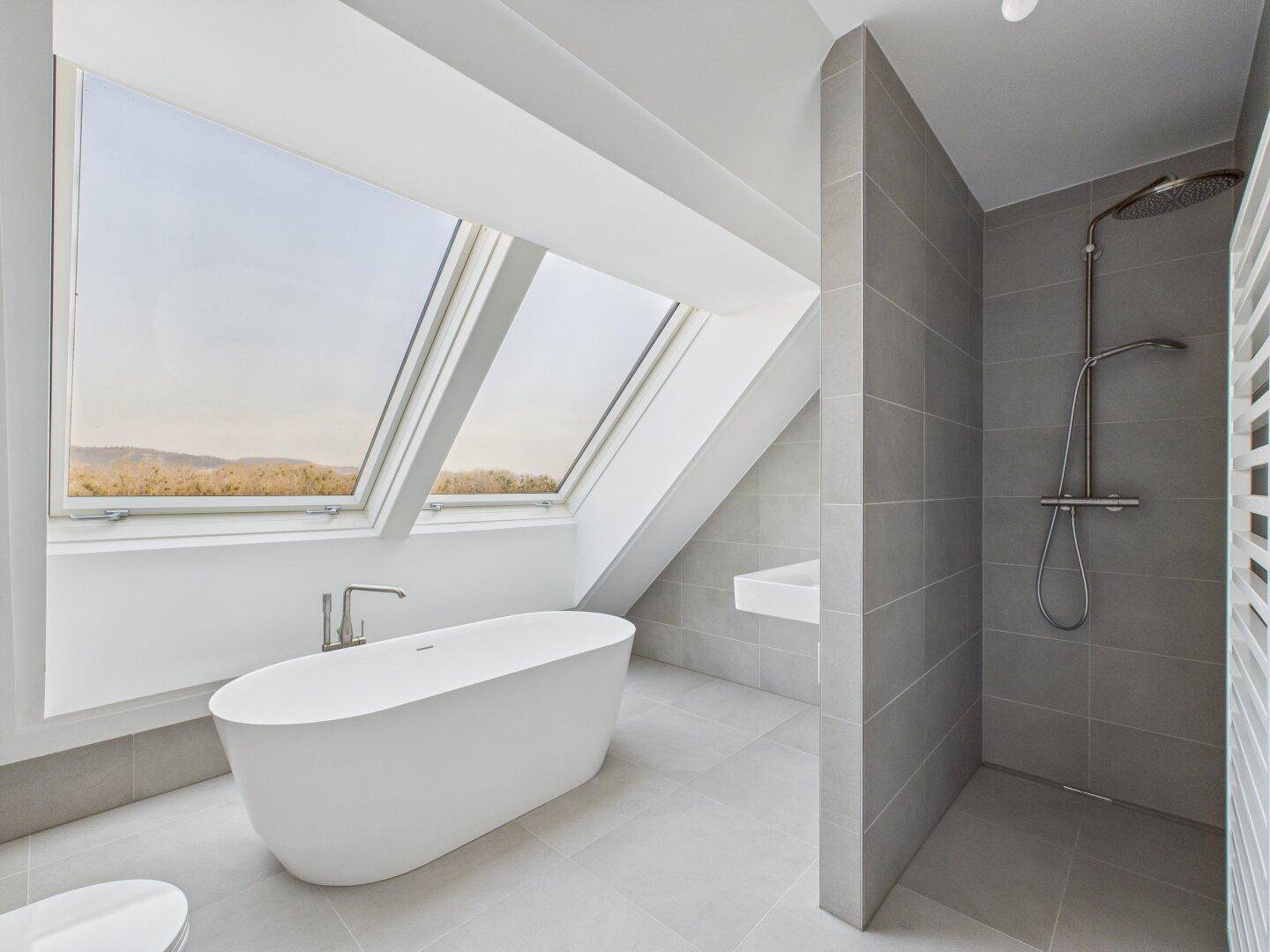 Modernes Badezimmer im Dachgeschoss mit freistehender Badewanne, Regendusche und Dachfenstern.