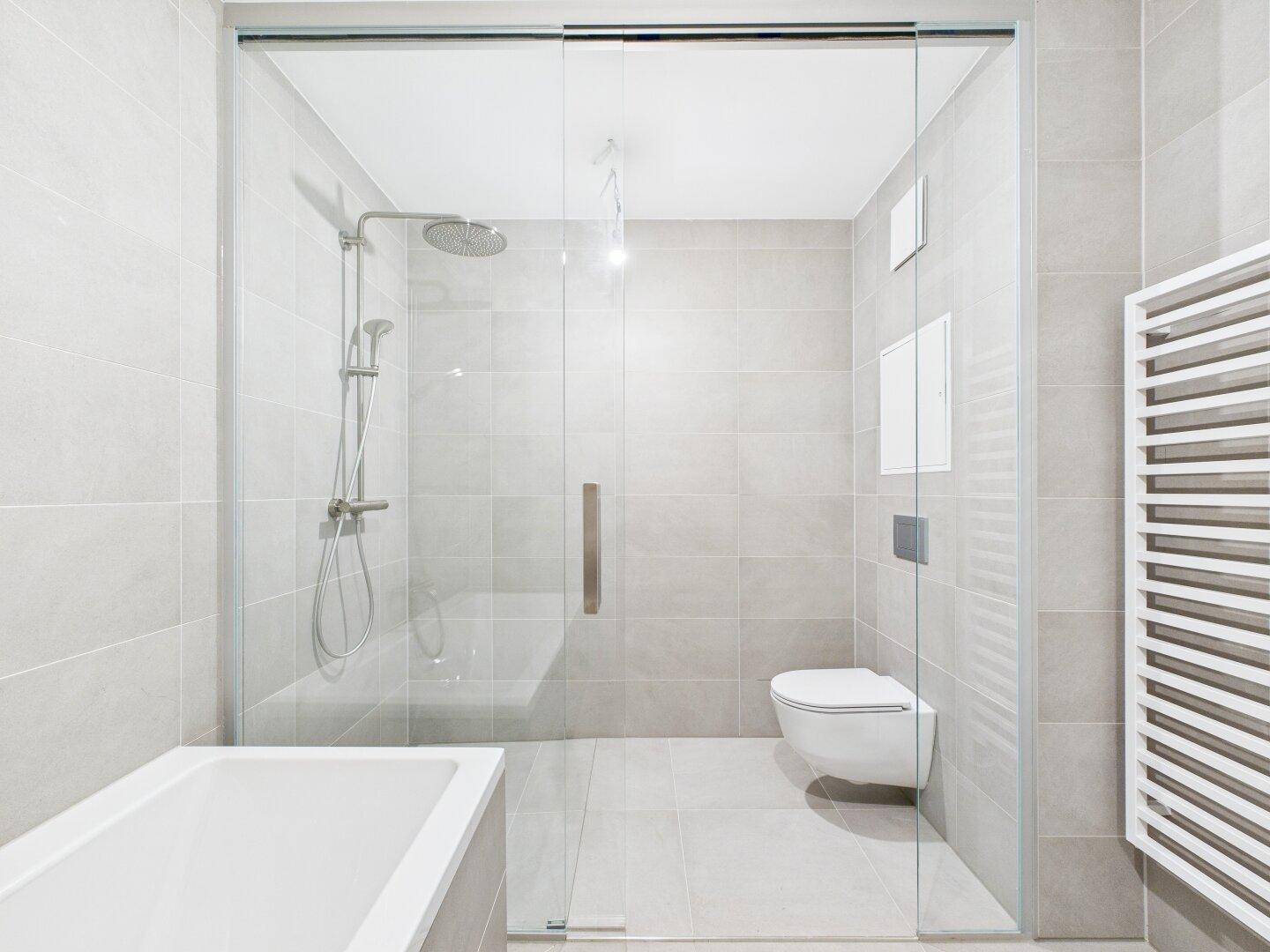 Modernes Badezimmer mit großer begehbarer Dusche, Wand-WC und praktischem Handtuchheizkörper.