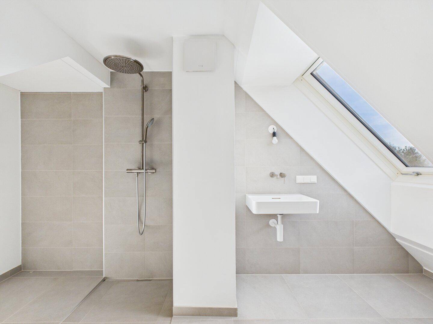 Helles Badezimmer mit begehbarer Dusche, modernem Waschbecken und Dachfenster.