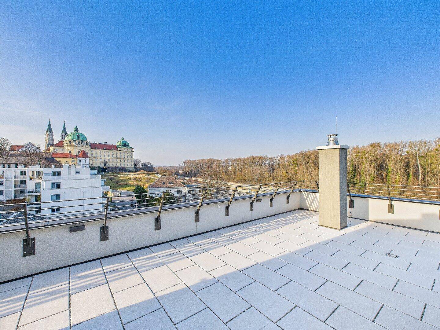 Weitläufige Dachterrasse mit Fliesenboden und beeindruckendem Blick auf die historische Stadtkulisse.