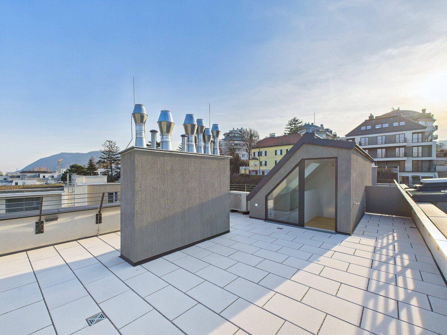 Geräumige Dachterrasse mit modernen Lüftungsschächten und einem Zugang zum Innenbereich.
