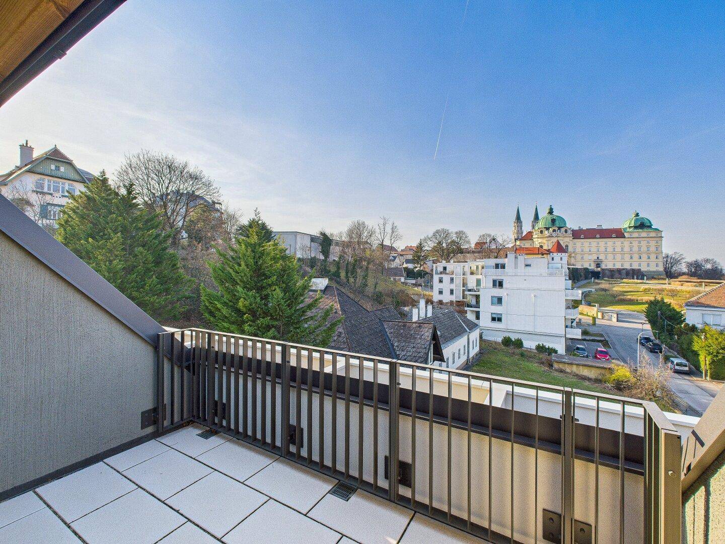 Kleiner Balkon mit Fliesenboden und weitem Blick auf die Stadt und eine historische Kirche.