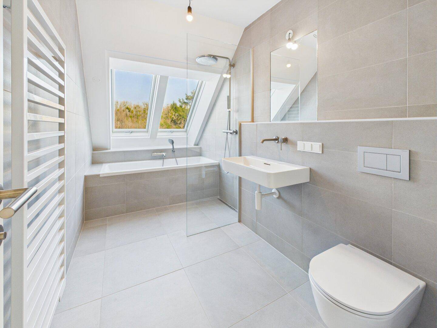 Helles, modernes Badezimmer mit Badewanne, Dusche, Waschbecken und beheiztem Handtuchhalter.