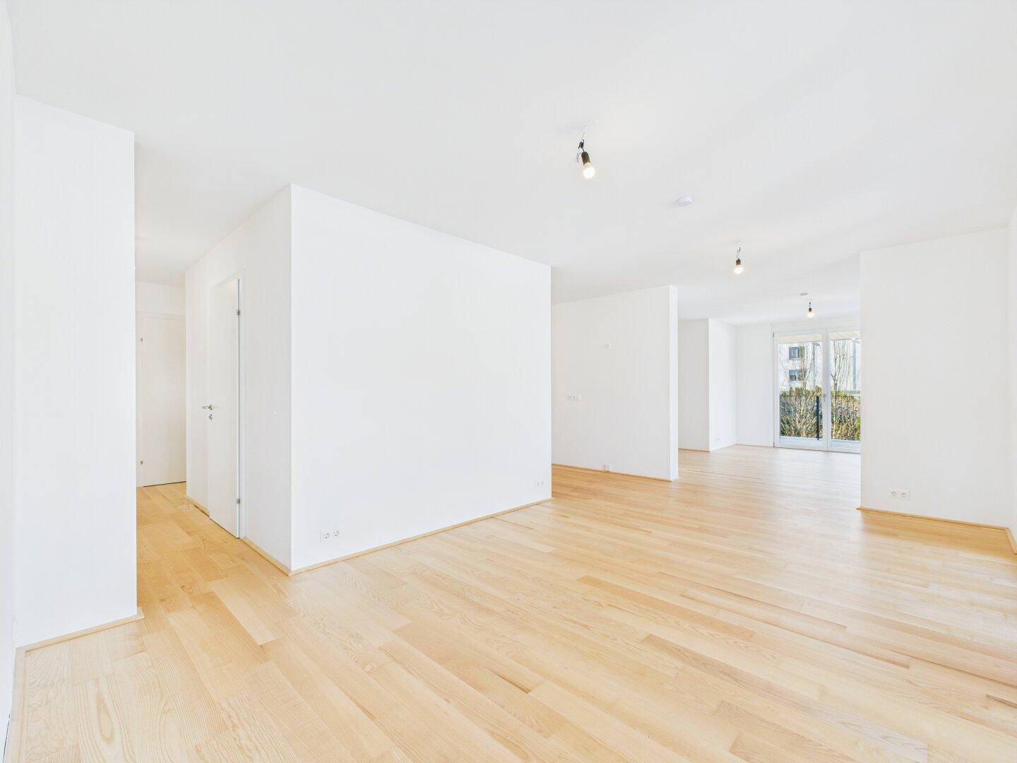 Geräumiges, helles Wohnzimmer mit Parkettboden und weißen Wänden, bereit zur Einrichtung.