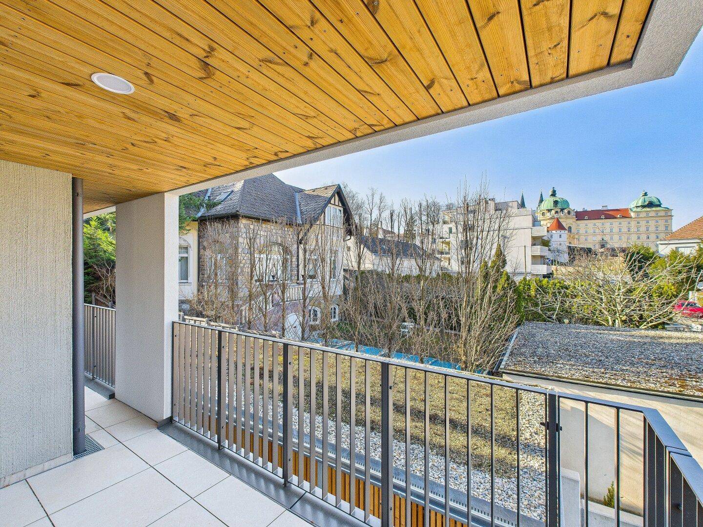 Geräumiger Balkon mit Fliesenboden und weitem Blick auf die historische Architektur und grüne Umgebung.