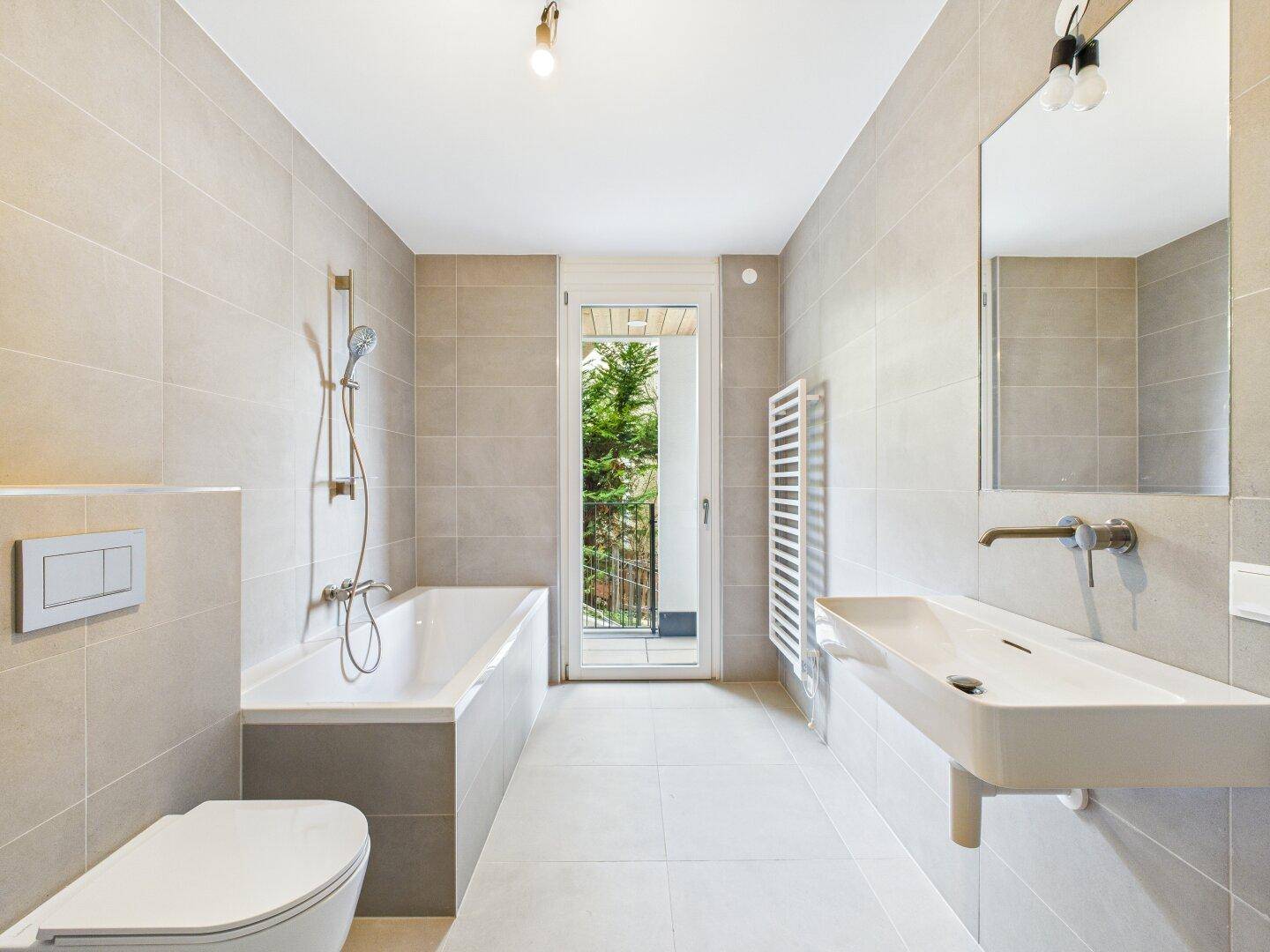 Modernes Badezimmer mit Badewanne, WC, Waschbecken und Zugang zu einem kleinen Balkon.