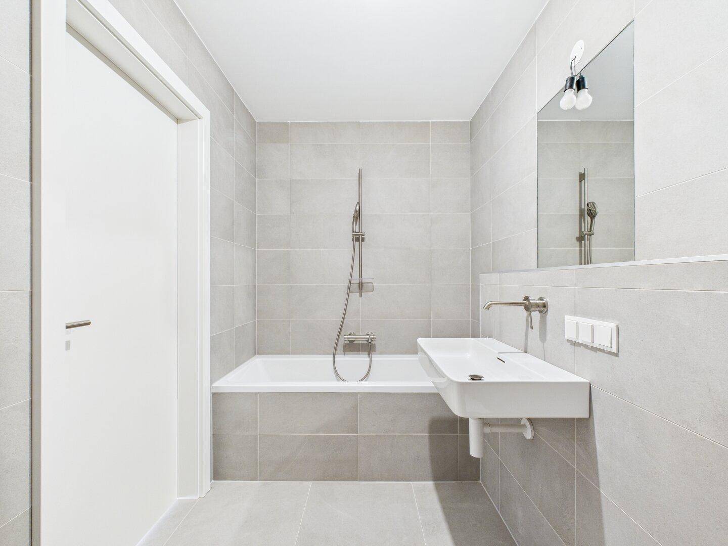 Modernes Badezimmer mit Badewanne, elegantem Waschbecken und großem Spiegel.