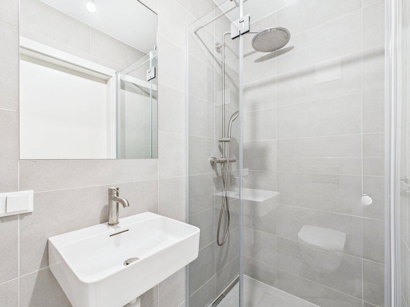 Modernes Badezimmer mit ebenerdiger Dusche, Waschbecken und großem Spiegel.
